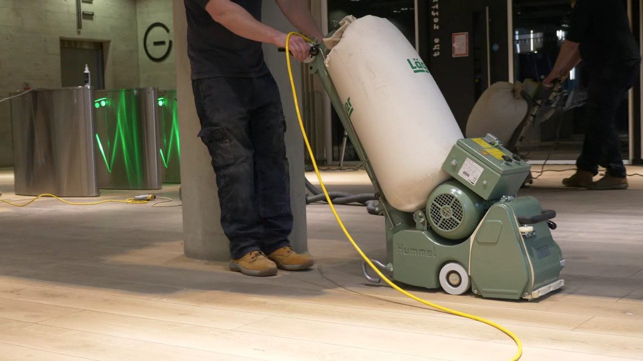 Wood Floor Sanding in eastbarnet on a light oak hardwood commercial lobby floor, with a technician using a Hummel dust-free sanding machine to smooth the planks.