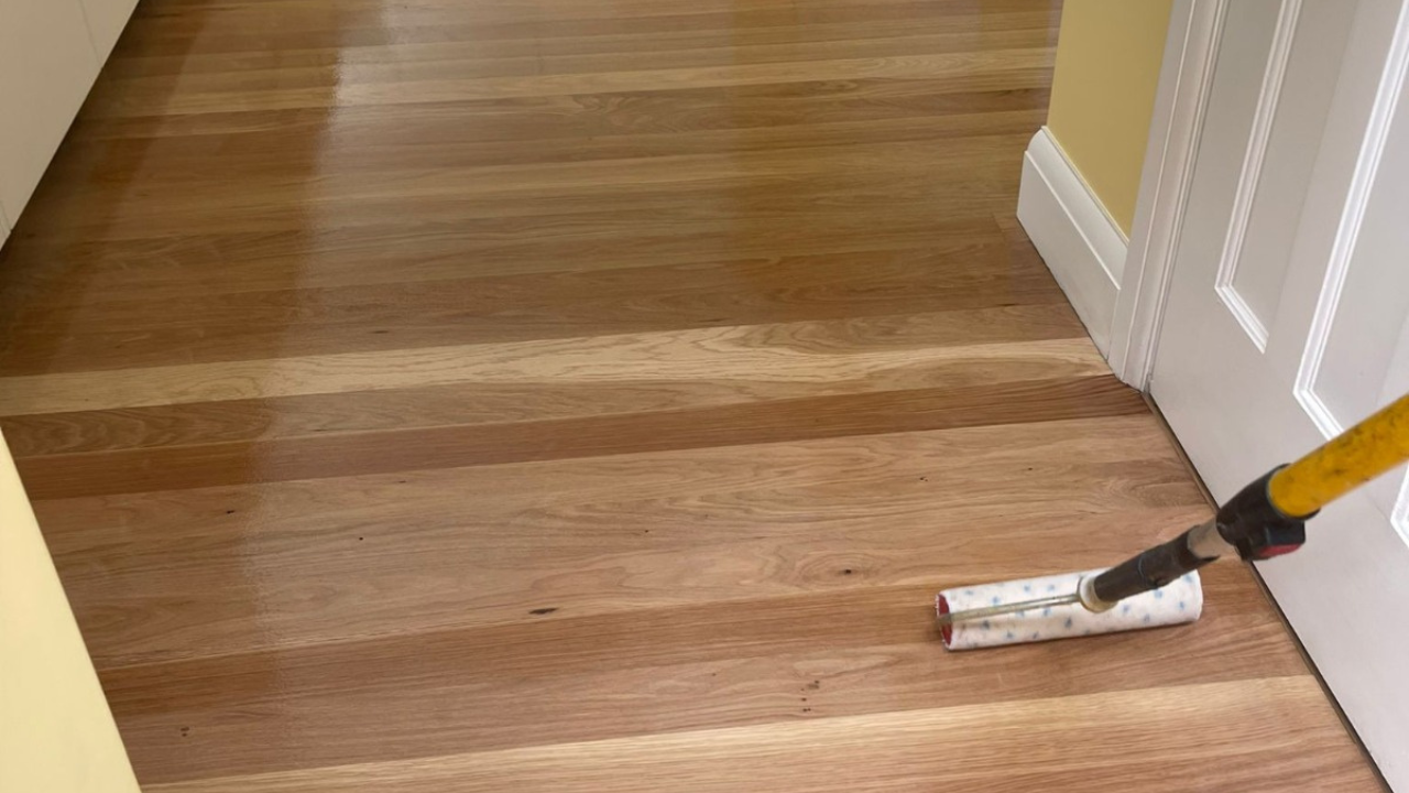 Wood Floor Sanding in eastbarnet on an oak hardwood plank hallway floor, with fresh clear finish being rolled on to reveal a smooth, rich grain.
