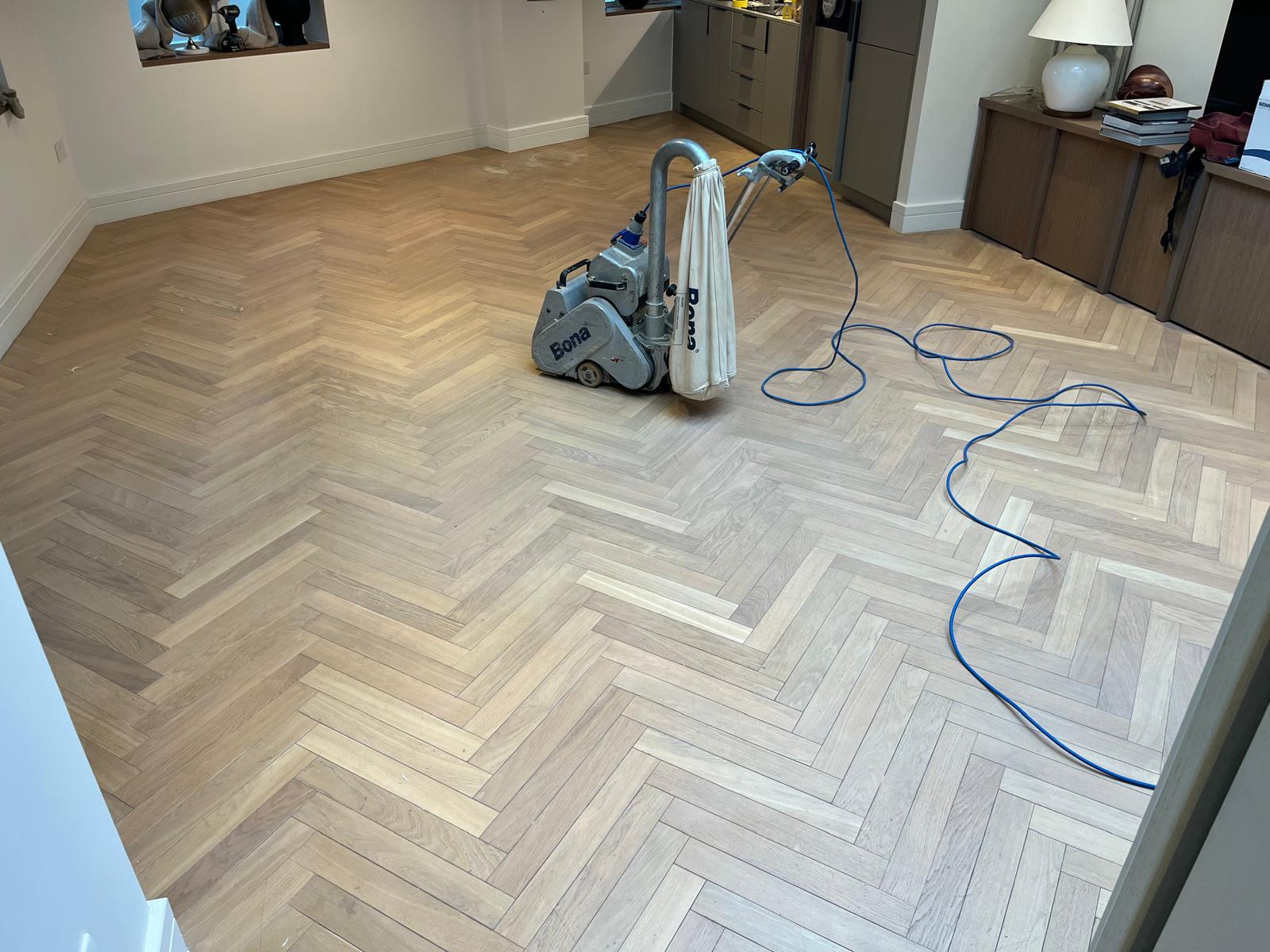 Wood floor sanding in eastbarnet on an oak herringbone parquet floor, with a professional Bona sanding machine restoring the living room surface ready for finishing.