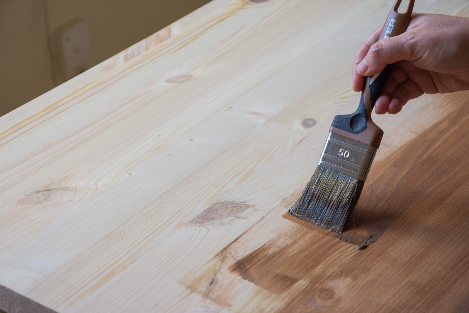 Wood Floor Sanding in eastbarnet shown through refinishing a solid pine wood worktop surface, with a hand brushing on protective stain after sanding.